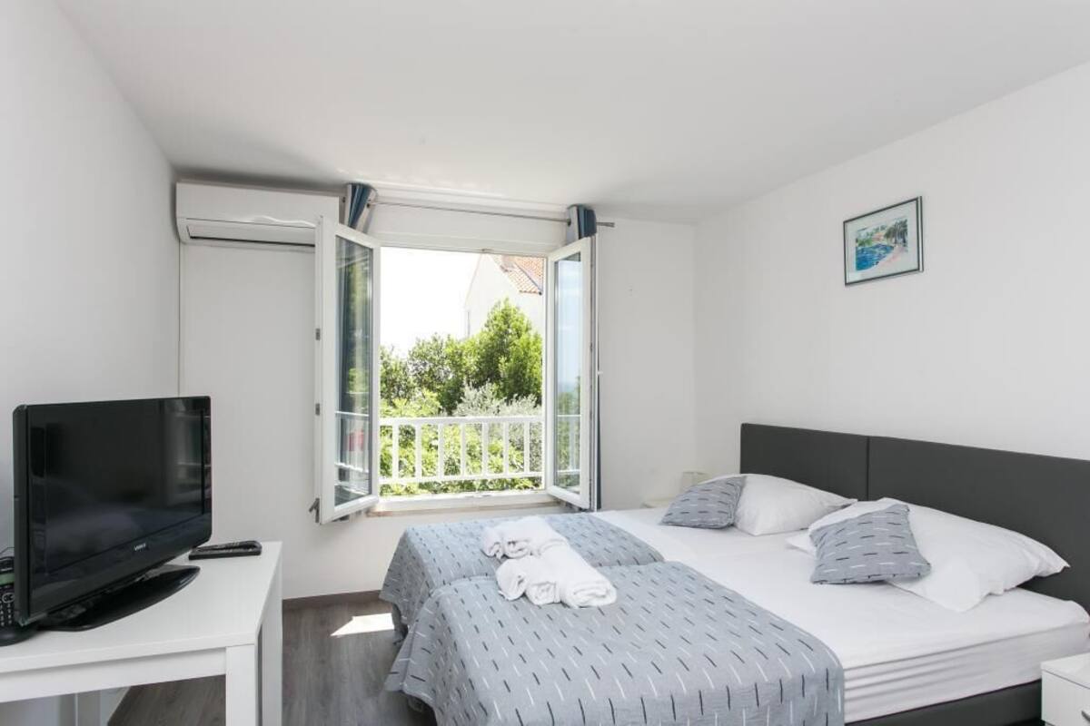 Habitación de hotel con cama, televisor, escritorio y balcón con vista a zonas verdes.