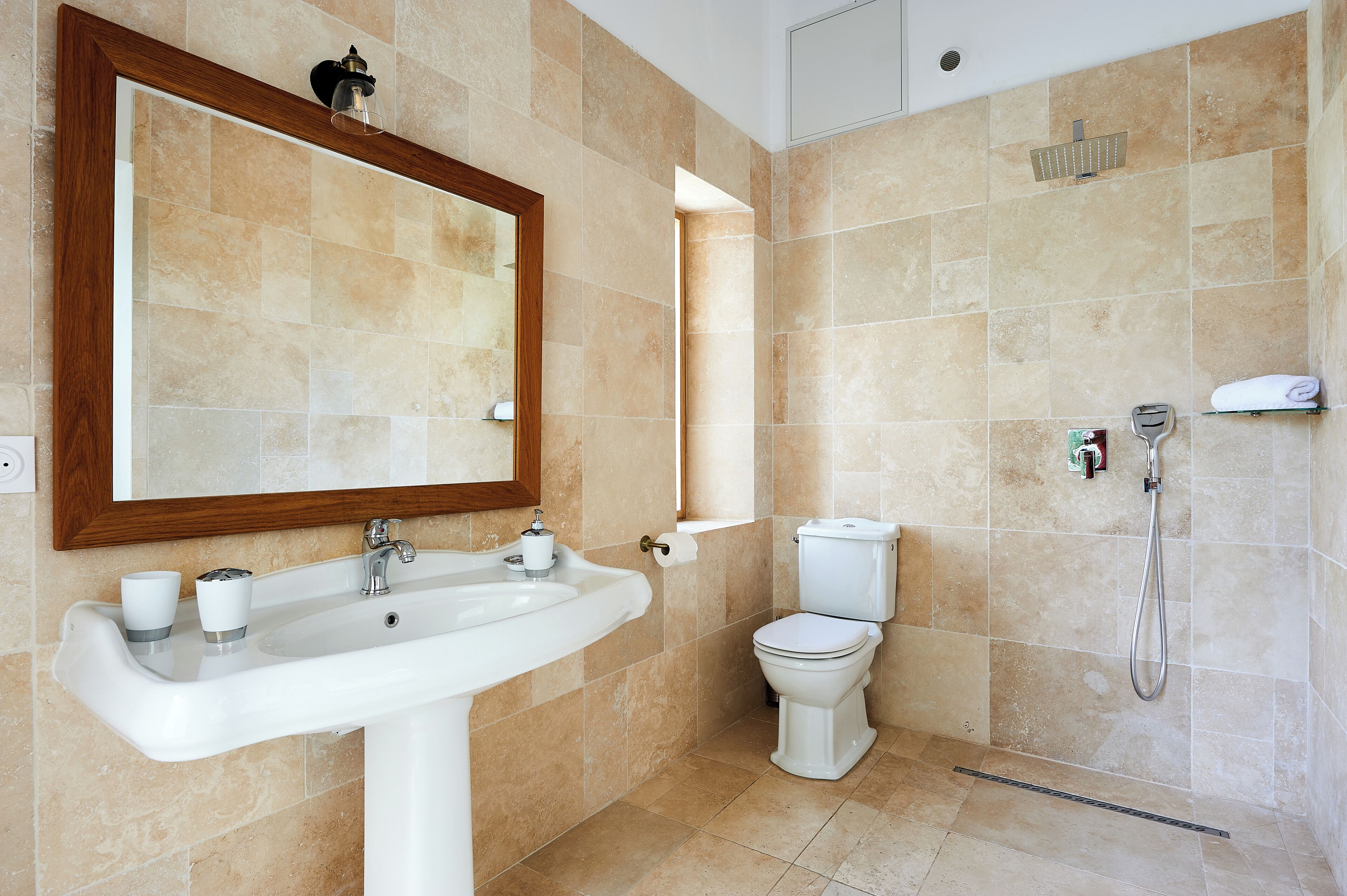A bathroom with a sink, mirror, toilet, and shower.