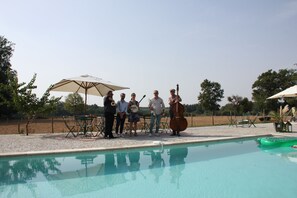 A group of people by a pool with a clear sky, outdoor furniture, and a calm environment. - DOMAINE DE BADINE (Saint-Sulpice-et-Cameyrac)