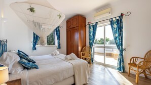 Un dormitorio con cama, armario de madera, una silla y balcón con vistas.