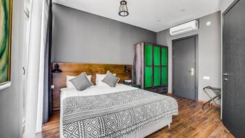Una camera da letto moderna con una testiera in legno, una coperta a motivi e un mobiletti verde.