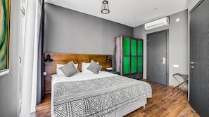 A modern bedroom with a wooden headboard, a patterned bedspread, and a green cabinet.