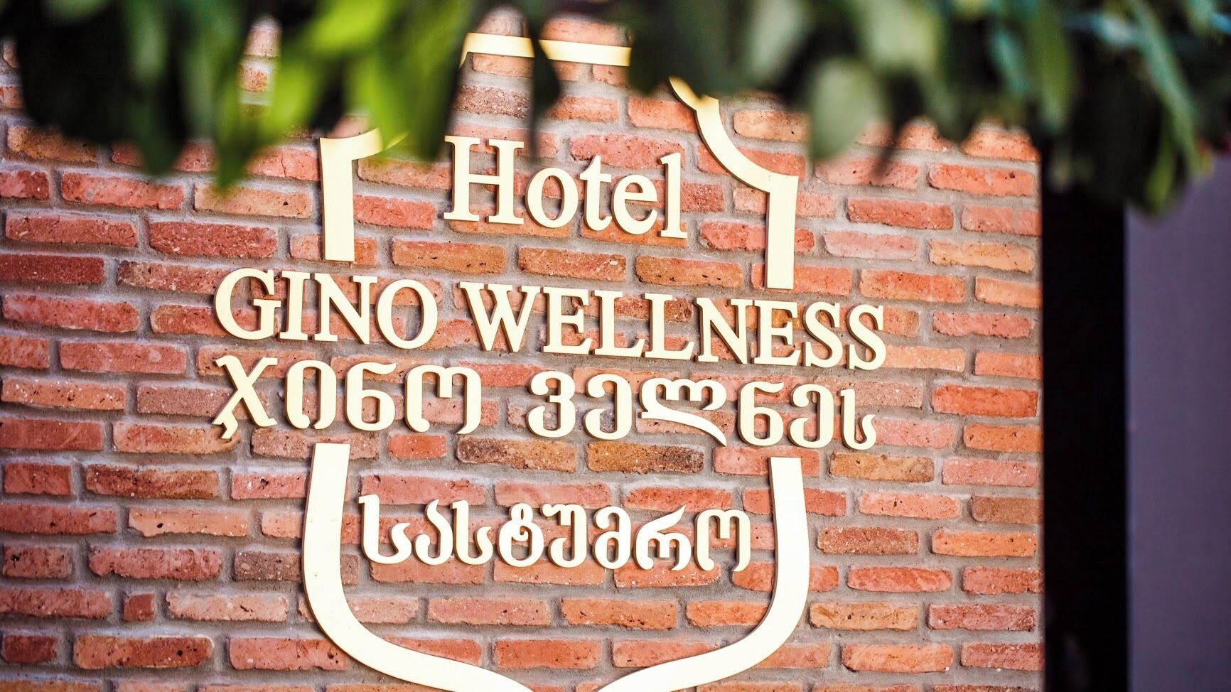Segnaletica per l'Hotel Gino Wellness con testo multilingue, tra cui inglese e un'altra lingua.