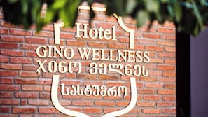 A sign for the Gino Wellness Hotel with multilingual text including English and another language.