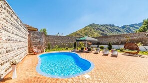 A swimming pool with lounge chairs and a view of mountains.