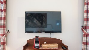 Un téléviseur à écran plat fixé au mur, au-dessus d’une console en bois.