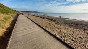 A boardwalk along a sandy beach with people walking and a clear sky. - Cozy Villa in Youghal, Co. Cork - Carleton Village  (Youghal)
