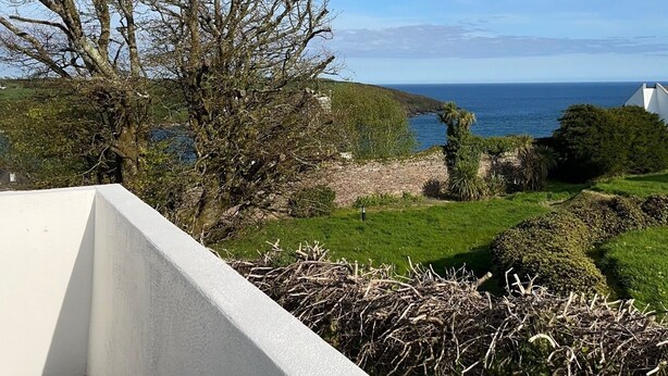 A balcony with a view of the sea, a tree, and a white building. - Cozy Villa in Youghal, Co. Cork - Carleton Village  (Youghal)
