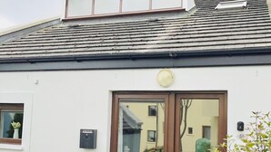 A white building with a brown door and window, a small porch, and a mailbox. - Cozy Villa in Youghal, Co. Cork - Carleton Village  (Youghal)