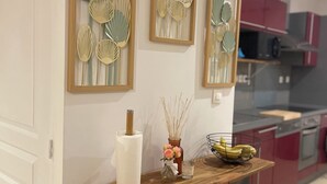 Une cuisine avec un plan de travail en bois, un meuble noir et une étagère murale agrémentée d’objets décoratifs.
