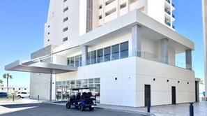 A modern building with a covered entrance, large windows, and a visible parking area with a golf cart.