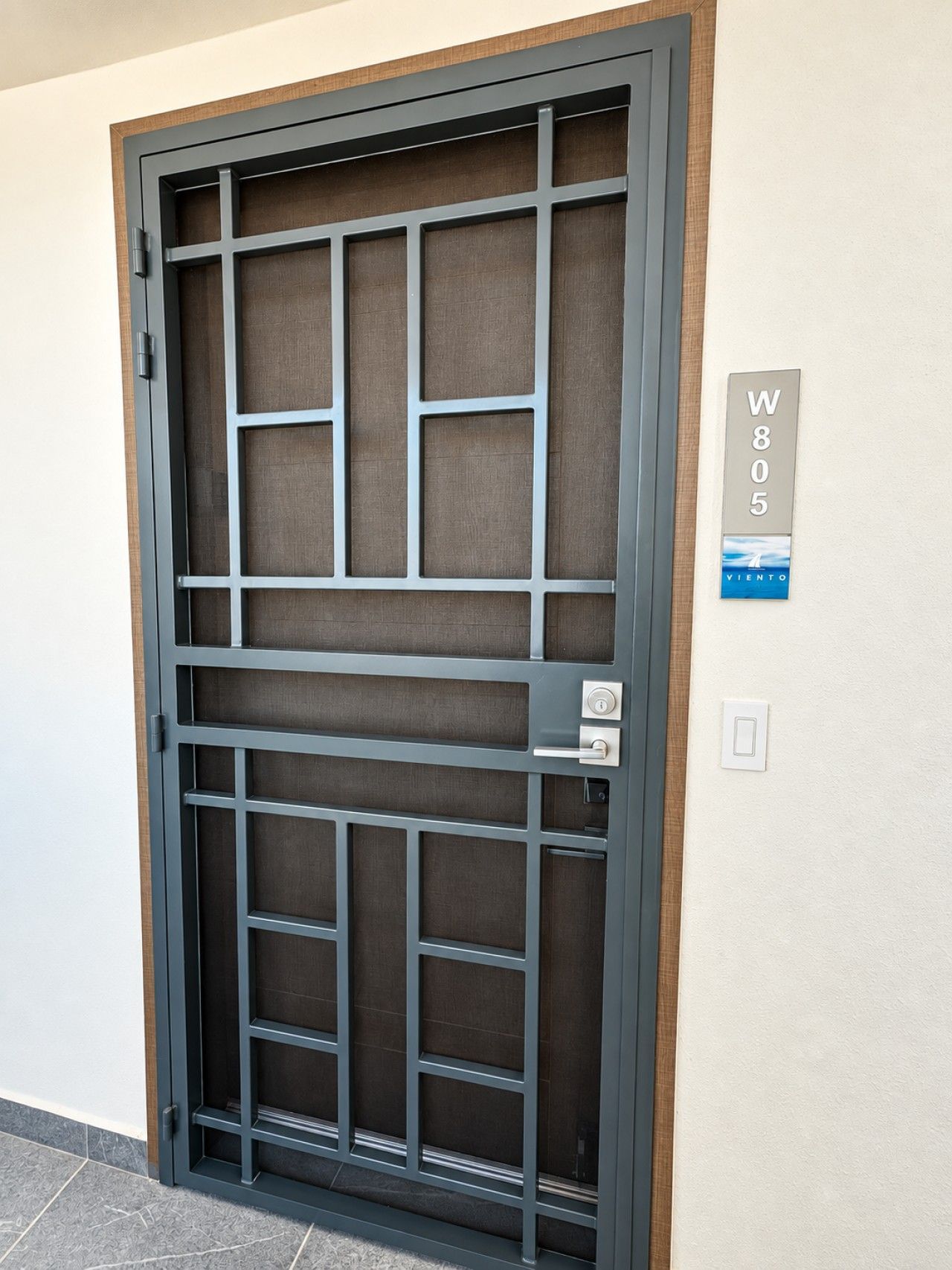 A door with a metal grid design, a keyhole, and a wall-mounted sign with the number 'W805'.