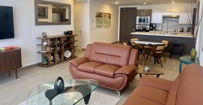 Ein Wohnzimmer mit einer Couch, einem Glastisch und einem Essbereich mit Stühlen und einem Tisch.