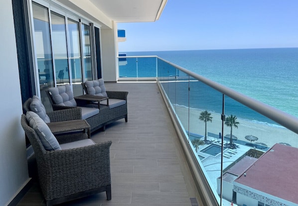 A balcony with wicker furniture and a view of the ocean.