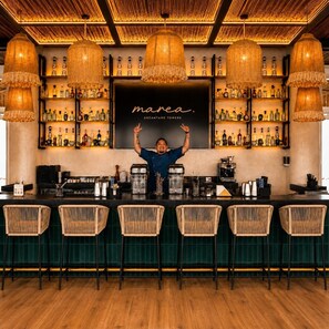 A bar with a bartender, wooden ceiling, and shelves of bottles.