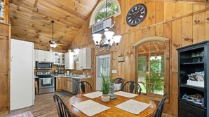 Ein Holzinterieur mit einem Esstisch, Stühlen, einer Uhr und einer Küchenzeile.