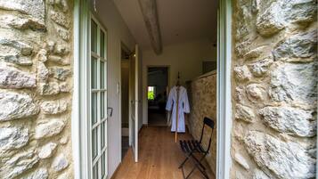 Un pasillo con paredes de piedra y suelo de madera, que conduce a una habitación con cama y ventana.