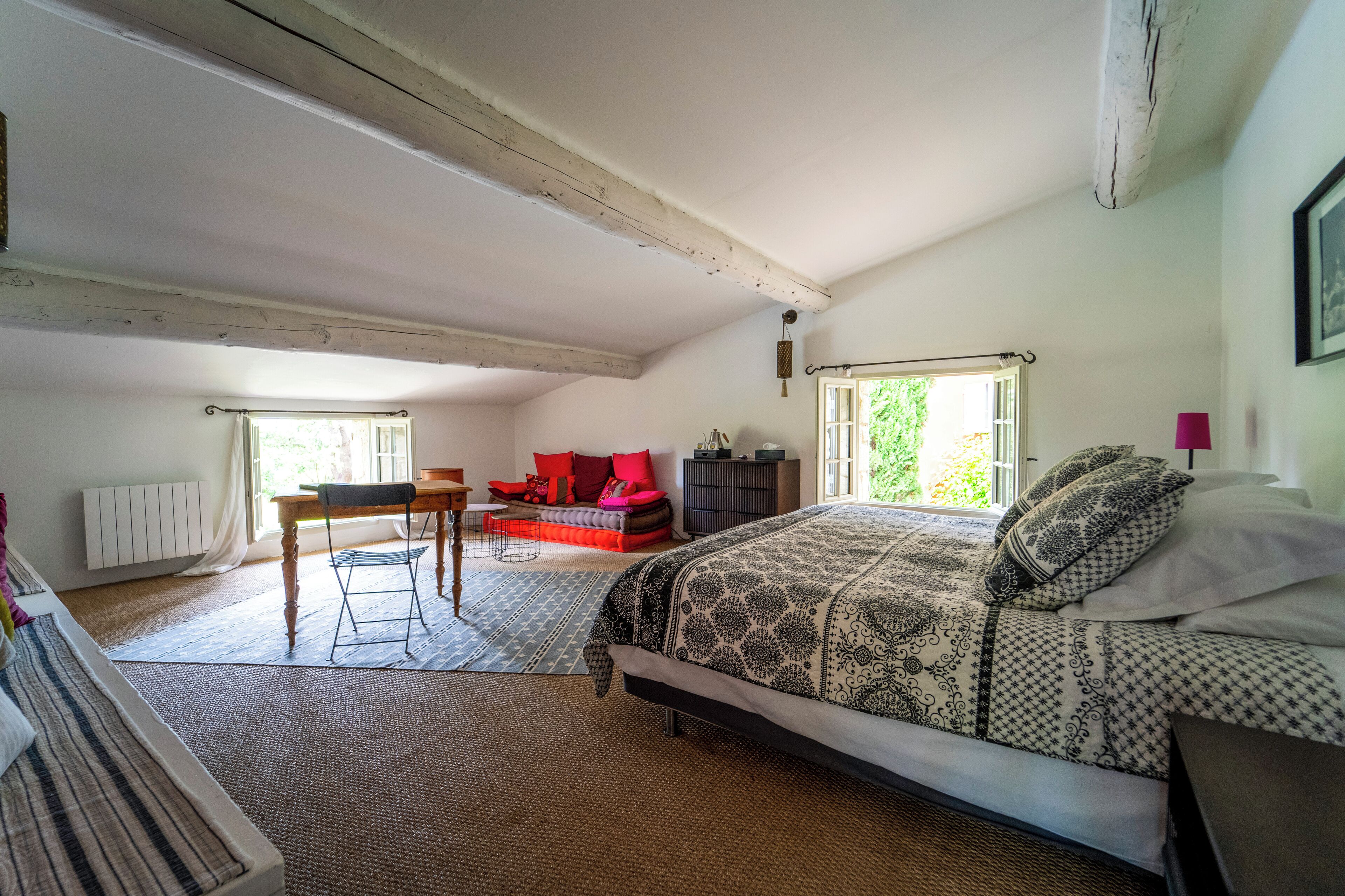 A bedroom with a large bed, a desk, and a sofa.