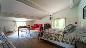 A bedroom with a large bed, a desk, and a sofa.