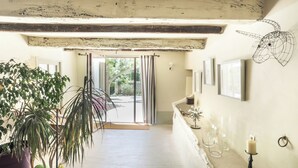 A hallway with a large potted plant, a small decorative sheep, and a candle on a stand. - Le Prieuré la Madelène (Malaucene)