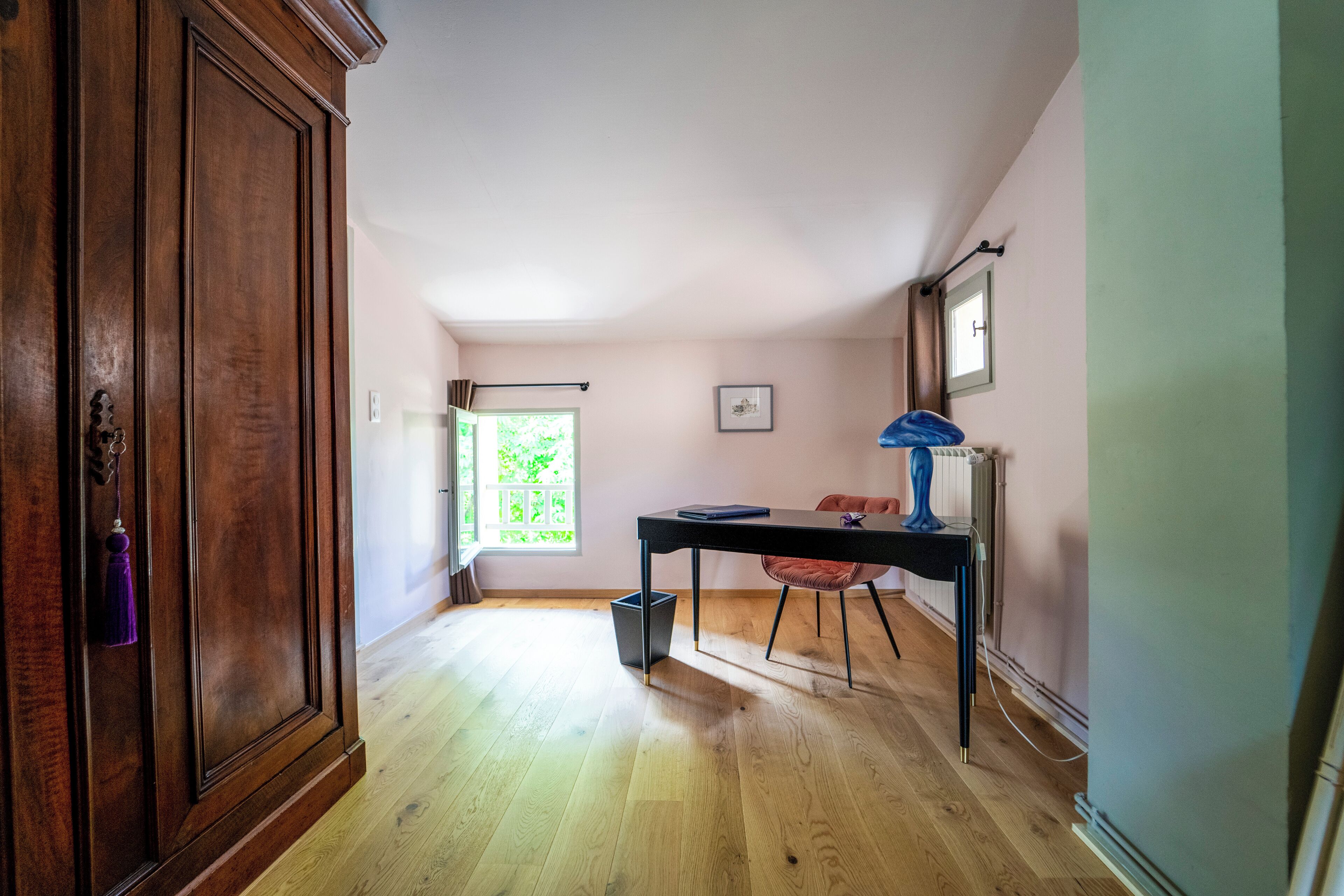 A hallway with a wooden door, a window, a table, and a chair.