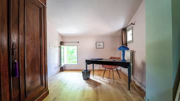 A hallway with a wooden door, a window, a table, and a chair.