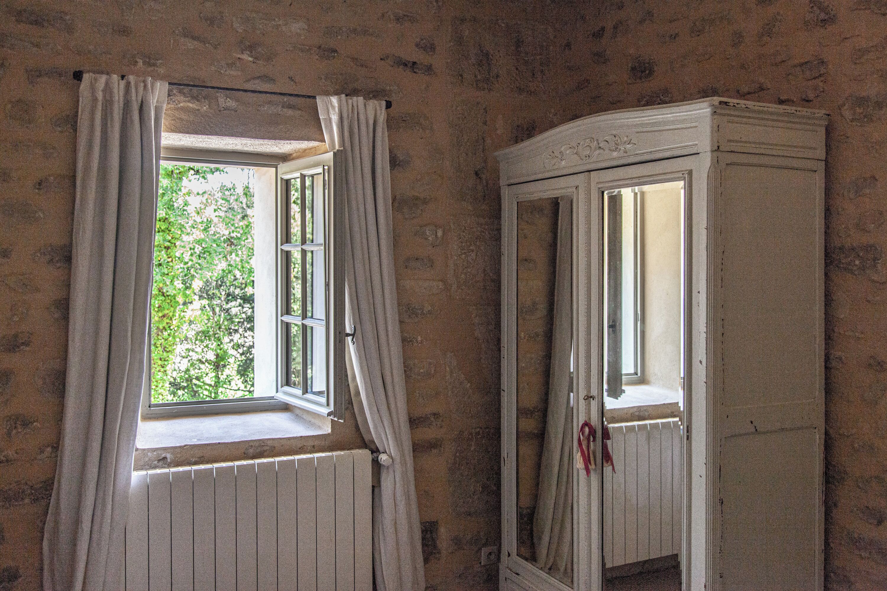 A room with a window and a white cabinet.