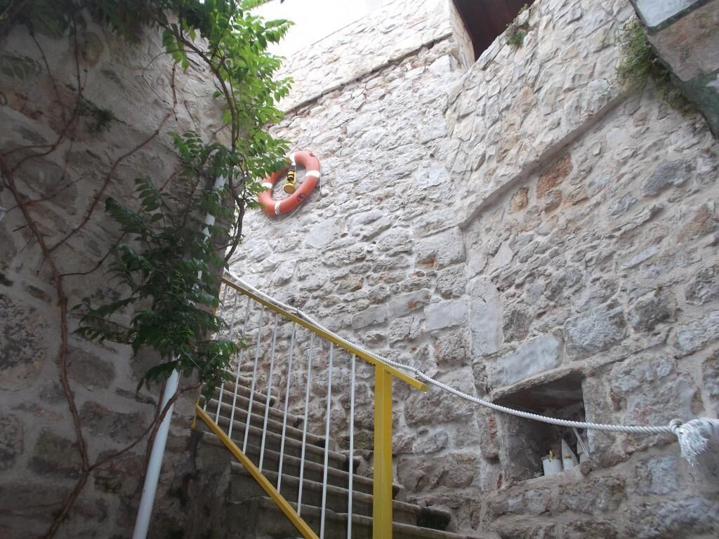 A stone wall with a yellow railing and a lifebuoy hanging on it.