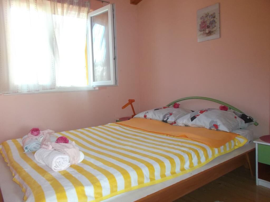 A single bed with a striped yellow and white bedspread, a green headboard, and a bedside table with a red lamp.