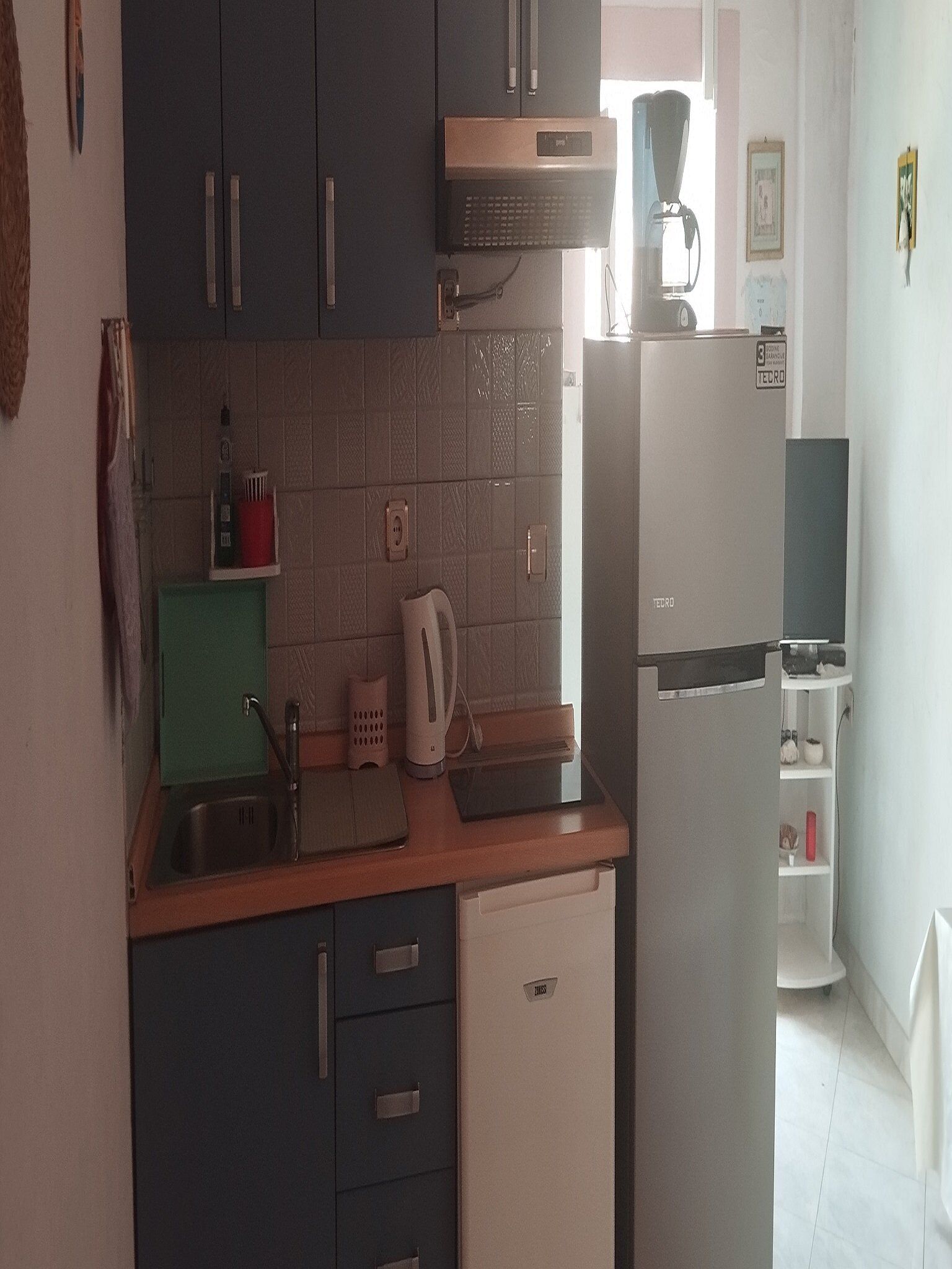 A compact kitchen with dark cabinets, a white refrigerator, and a coffee maker on the counter.