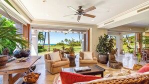 A spacious living area with a view of the ocean, furnished with sofas, a coffee table, and potted plants. - Golf Villa 1102–Prime Location & Ocean Views | Onsite Staff & Daily Housekeeping (Kailua Kona)