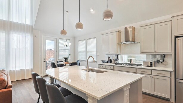 Una cocina moderna con una isla central, armarios blancos e iluminación colgante.