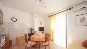 A compact kitchen with a dining area, a clock, and a TV on the wall. - Apartments Mira (Supetar)