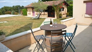 A patio with a round wooden table and two chairs, a small pool, and a house with a tiled roof in the background. - Maison de Campagne au Coeur de la Double Avec Piscine (Échourgnac)