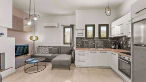 A modern kitchen with a built-in oven, a dining area with a round table, and a gray sofa.
