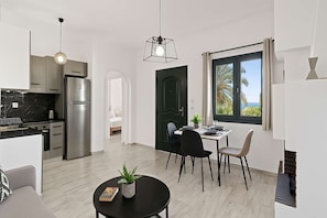 A modern kitchen with a refrigerator, stove, and dining area with chairs and a table.