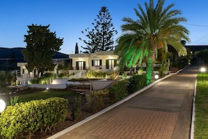 A modern villa with a pool, outdoor seating, and a well-lit pathway.