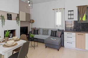 A modern apartment with a dining area, a grey sofa with cushions, a small side table, and a kitchen with a black countertop and cabinets.