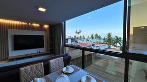 Un comedor moderno con un amplio ventanal que ofrece vistas a una playa y palmeras.