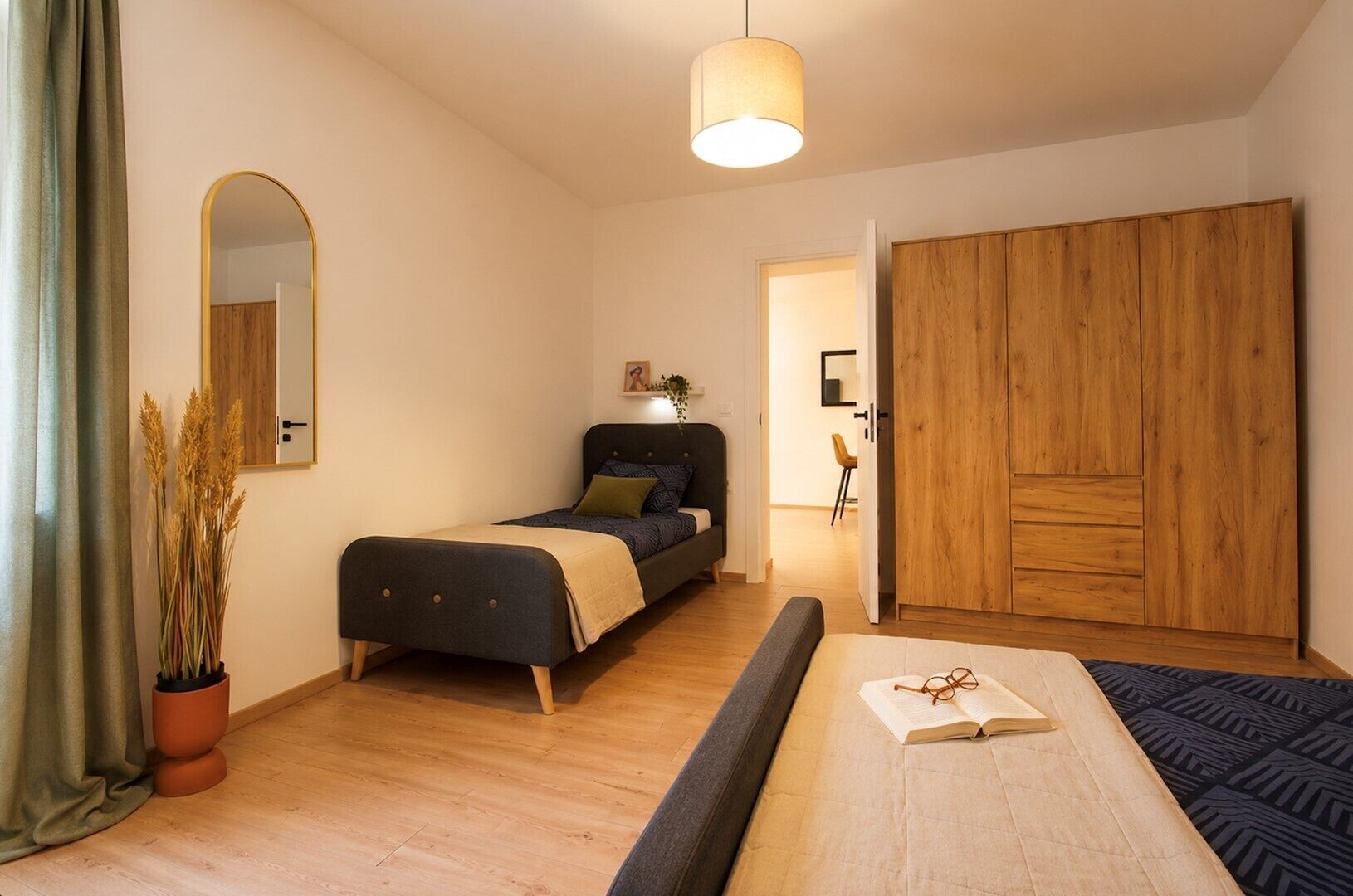 Une chambre à coucher avec un lit, une table de chevet et une grande armoire en bois.