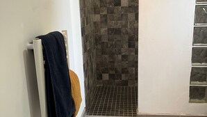 Ein Badezimmer mit Duschbereich, gefliesten Wänden und Boden.