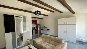 Ein modernes Wohnzimmer mit einem beigen Sofa, einem Glastisch und einer topfgestellten Pflanze.