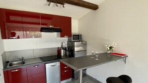 Eine moderne Küche mit roten Schränken, Edelstahlgeräten und einem Barhocker.