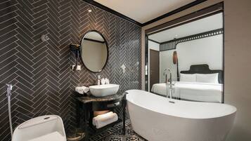 A modern bathroom with a freestanding bathtub, a round mirror, a vanity with a sink, and a toilet.