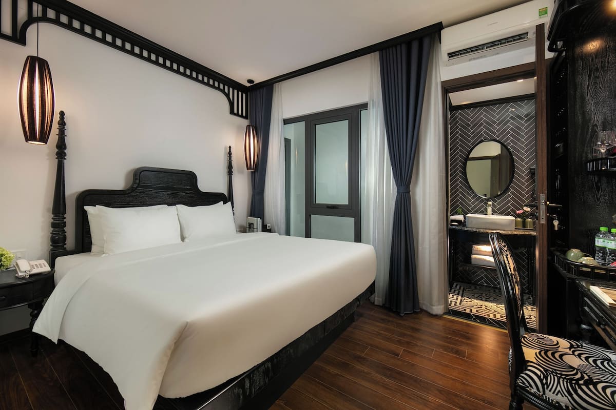 Habitación de hotel con una cama grande, un teléfono en la mesita de noche, un espejo y una pequeña mesa con artículos de aseo.