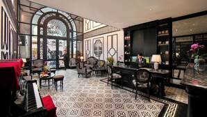 A spacious lobby with a grand piano, comfortable seating, and a large window offering a view. - Hanoi Le Chateau Hotel & Spa (Hanoi)