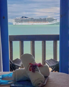 A balcony with a view of a cruise ship, a towel, and a flower. - Vila Bela-Emília (Búzios)