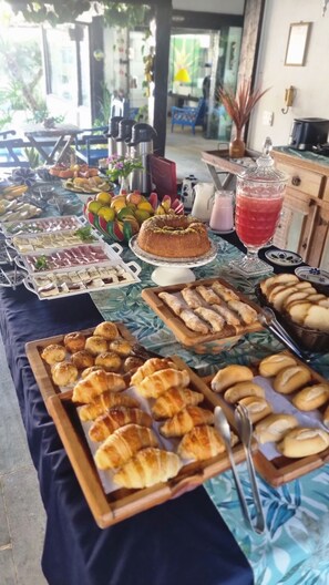Ein reichhaltiges Buffet mit verschiedenen Speisen, darunter Gebäck, Obst und eine Torte.