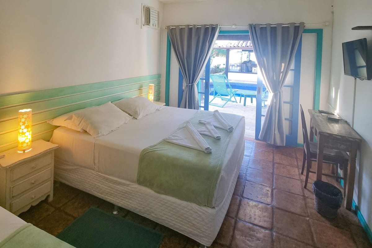 A hotel room with a bed, a desk, a chair, a TV, and a window with curtains.