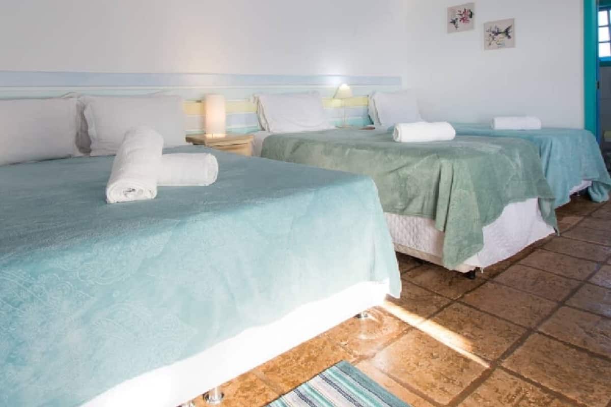A hotel room with two beds, a tiled floor, a striped ceiling, and a small window.